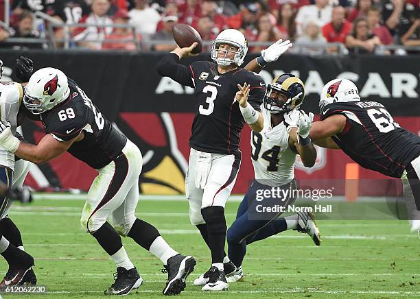 Quarterback Carson Palmer of the Arizona Cardinals looks to make a pass in front of defensive end Robert Quinn of the Los Angeles Rams during the...