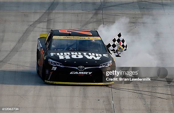 Martin Truex Jr., driver of the Furniture Row/Denver Mattress Toyota, celebrates with the checkered flag after winning the NASCAR Sprint Cup Series...