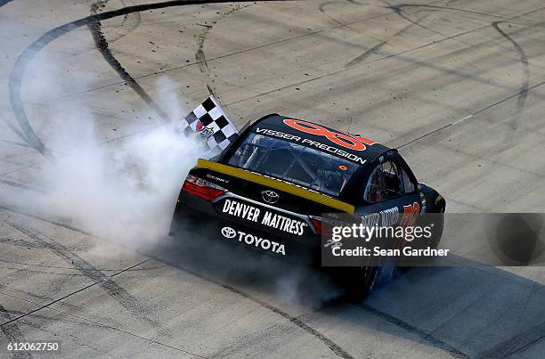 Martin Truex Jr., driver of the Furniture Row/Denver Mattress Toyota, celebrates with the checkered flag after winning the NASCAR Sprint Cup Series...