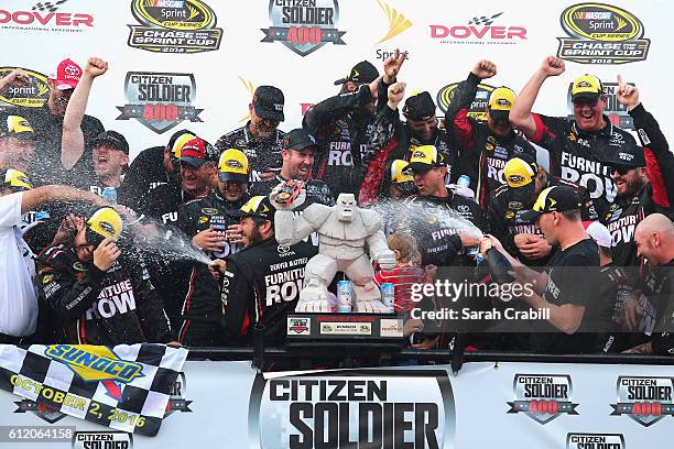 Martin Truex Jr., driver of the Furniture Row/Denver Mattress Toyota, celebrates with the trophy in Victory Lane after winning the NASCAR Sprint Cup...