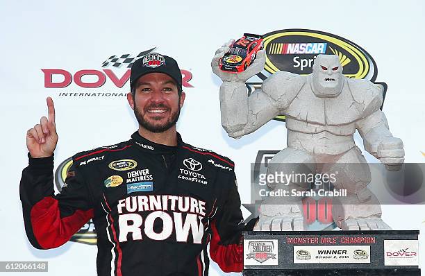 Martin Truex Jr., driver of the Furniture Row/Denver Mattress Toyota, poses with the trophy in Victory Lane after winning the NASCAR Sprint Cup...