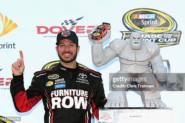 Martin Truex Jr., driver of the Furniture Row/Denver Mattress Toyota, poses with the trophy in Victory Lane after winning the NASCAR Sprint Cup...