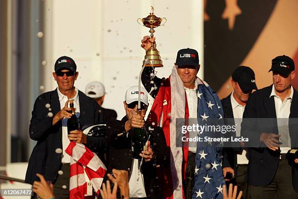 Zach Johnson of the United States sprays champagne as captain Davis Love III holds the Ryder Cup during the closing ceremony of the 2016 Ryder Cup at...
