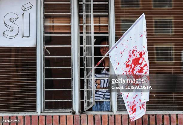 Woman stands near a white flag splashed in red as if it were blood after knowing the results of a referendum on whether to ratify a historic peace...