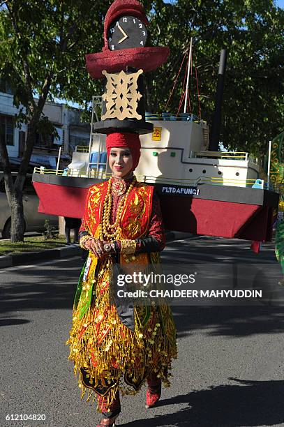 This picture taken on October 2, 2016 shows an Acehnese model carrying a model copy of a ship destroyed during the 2004 tsunami and a clock...