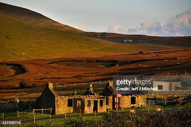 Sun shines on an old building and telephone box on the Island of Foula on October 2, 2016 in Foula, Scotland. Foula is the remotest inhabited island...