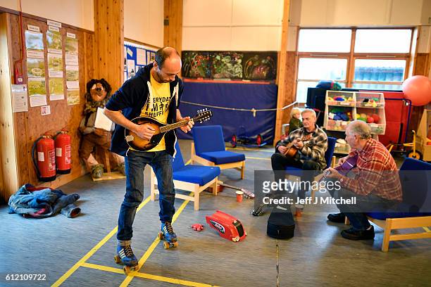 Stuart Taylor plays a tune while on roller skates with Davie Henry and Jim Grear at the primary school coffee morning on the Island of Foula on...