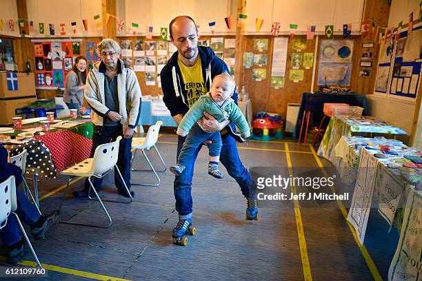Stuart Taylo, on roller skates, carries the youngest resident eight month old Elan Grear during the primary school coffee morning on the Island of...