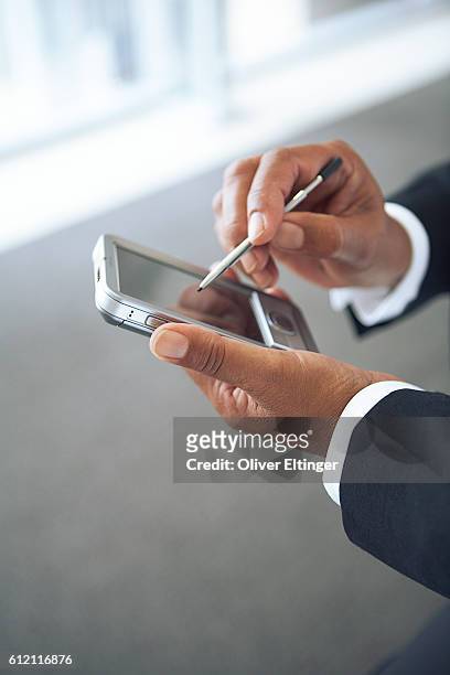 businessman using a personal digital assistant - oliver eltinger stock-fotos und bilder