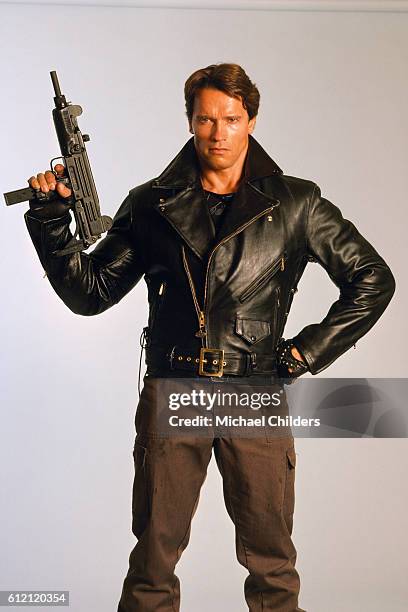 Actor Arnold Schwarzenegger as Terminator with a hand on his hips, holds a machine gun pointed upwards for 'The Terminator' studio shot, April 1st...