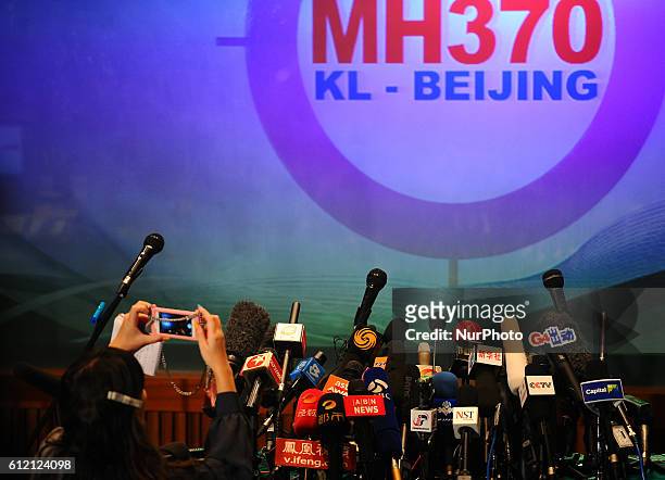 Journalist takes pictures of the hundreds of microphones propped up before the press conference of the missing Malaysia Airline, MH370 as it closes...