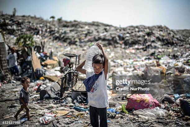 Boy carries a container filled with water over his back at a garbage dumpsite during Earth Day in Las Pinas, south of Manila, Philippines, April 22,...