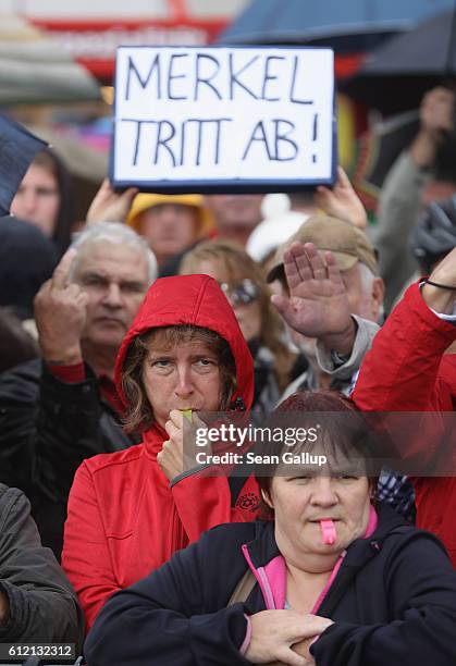 Angry onlookers, including one holding a sign that reads: "Merkel resign," shout "Merkel muss weg!" and "Volksverraeter!" outside the Semperoper...