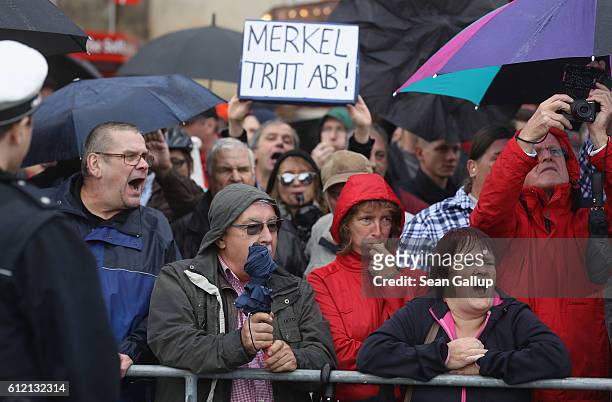 Angry onlookers, including one holding a sign that reads: "Merkel resign," shout "Merkel muss weg!" and "Volksverraeter!" outside the Semperoper...