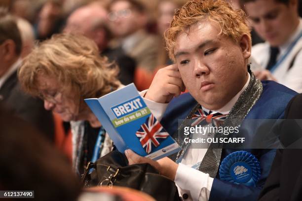 Delegate reads a leaflet entitled "BREXIT, how do we do it?" as he sits in the audience on the second day of the annual Conservative Party conference...