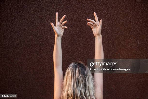 woman with arms raised above her head, rear view - stretching hands behind head rear view stock-fotos und bilder