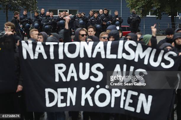 Police watch as leftists carrying a banner that reads: "Nationalism out of the heads" heckle supporters of the Pegida movement marching on German...