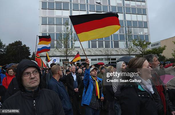 Supporters of the Pegida movement, including some waving German flags, listen to speeches after marching on German Unity Day on October 3, 2016 in...