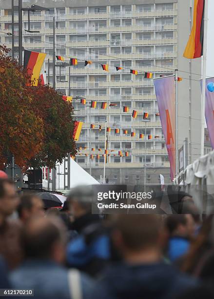People walk under Germn flags fluttering above in the city center during celebrations to mark German Unity Day on October 3, 2016 in Dresden,...