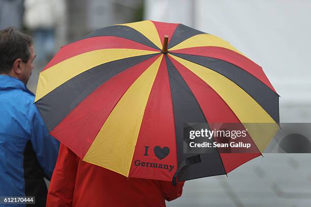 Woman holding an umbrella with the colors of the German flag walks to join a march by supporters of the Pegida movement on German Unity Day on...