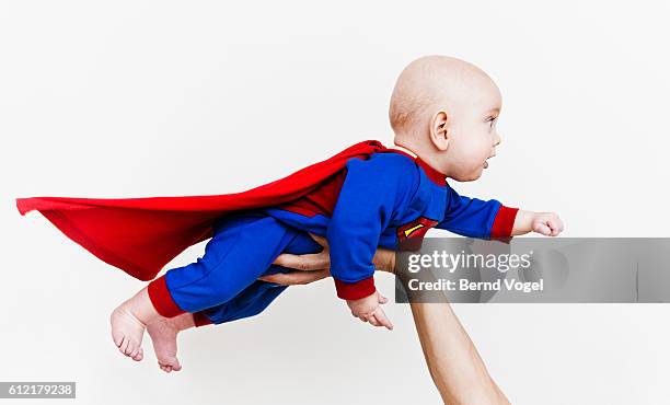 baby wearing super hero outfit - baby being held stockfoto's en -beelden