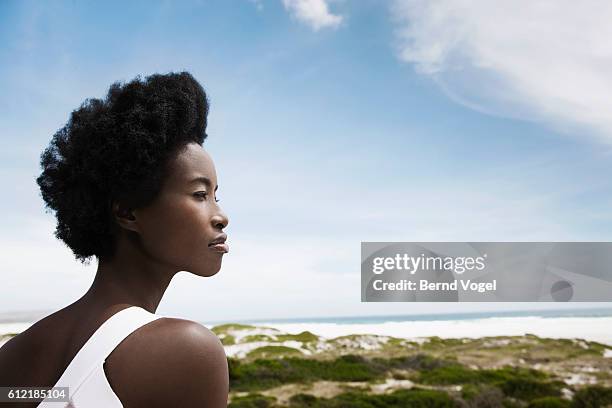 woman with afro by beach - afro frisur stock-fotos und bilder