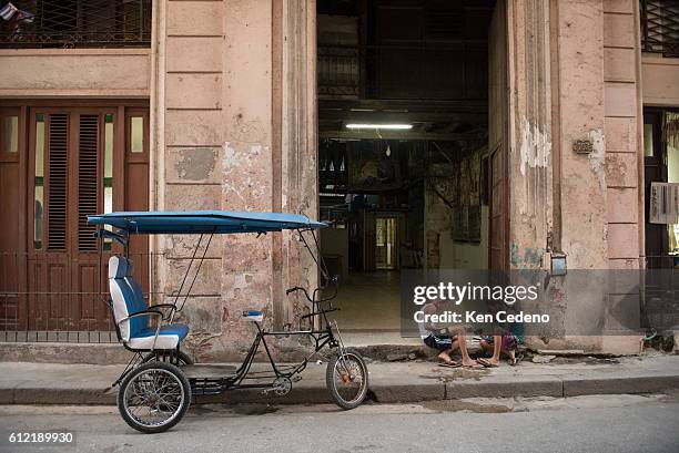 Two young boys play cards in a doorway next to a bicycle cab in the old Havana neighborhood of Havana, Cuba January 4, 2015. The United States...