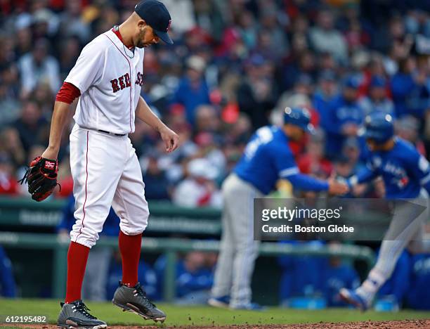 Boston Red Sox starting pitcher David Price paws the mound at left after the Blue Jays player Devon Travis, background, hit a solo home run in the...