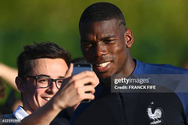 France's midfielder Paul Pogba poses for a selfie with a supporter before a training session in Clairefontaine-en-Yvelines near Paris on October 3,...