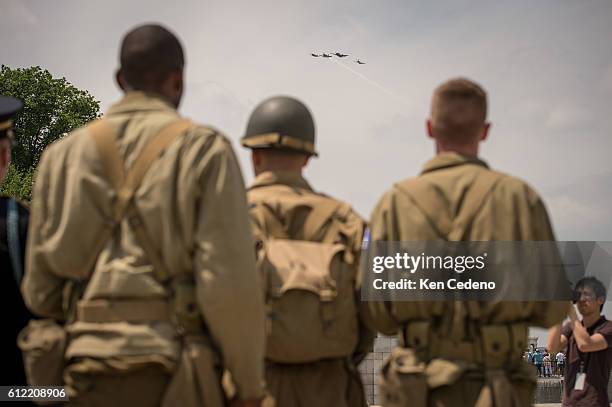 Reenactment soldiers from Ft. Myer watch as vintage WWII planes perform the "missing man formation," during a diverse array of World War II aircraft...