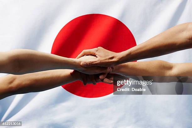 Four hands clasped in front of japanese flag