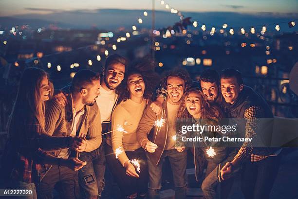 rooftop party with sparklers at night - friends with sparkler fireworks stock pictures, royalty-free photos & images