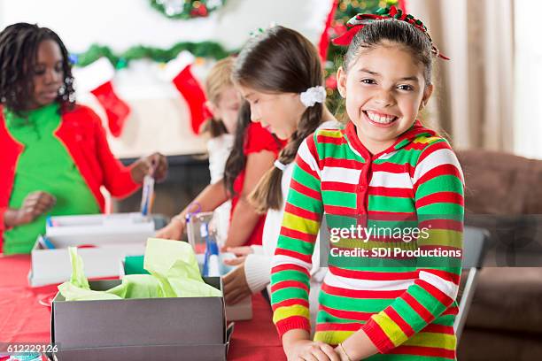 cute girl smiles while working on project at christmastime - schoenendoos stockfoto's en -beelden