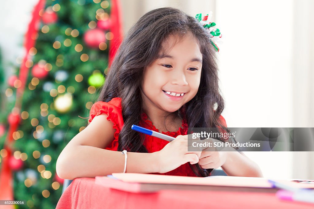 Pretty girl smiles whilte making homemade Christmas card