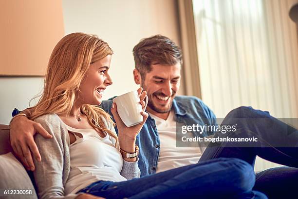 couple drinking coffee on the sofa - sharing coffee stockfoto's en -beelden