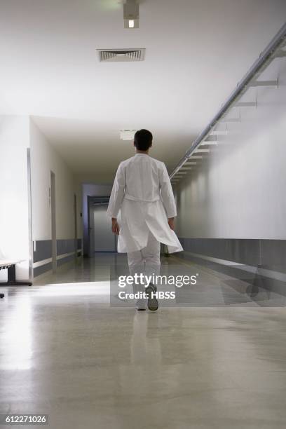 doctor walking down corridor - doctor looking down stock pictures, royalty-free photos & images