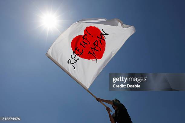 Person Waving Japanese Flag with the Words Rise Up Japan