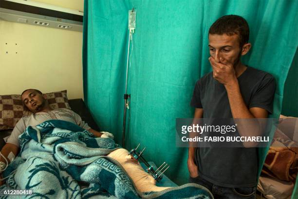 Friend visits a fighter loyal to Libya's Government of National Accord forces at Misrata Central Hospital, between Sirte and Tripoli, on October 3 a...