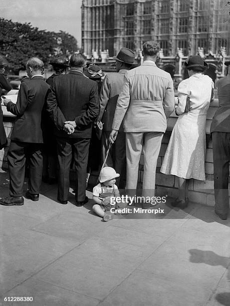 Our Picture Shows; A young child bored with the situation decides to sit down while his parents look on.