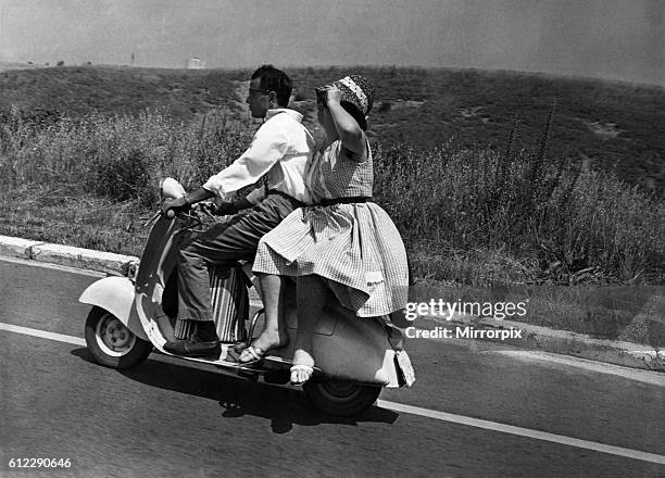 Girl riding sidesaddle on a scooter during a trip in the Italian countryside. June 1962 P04732