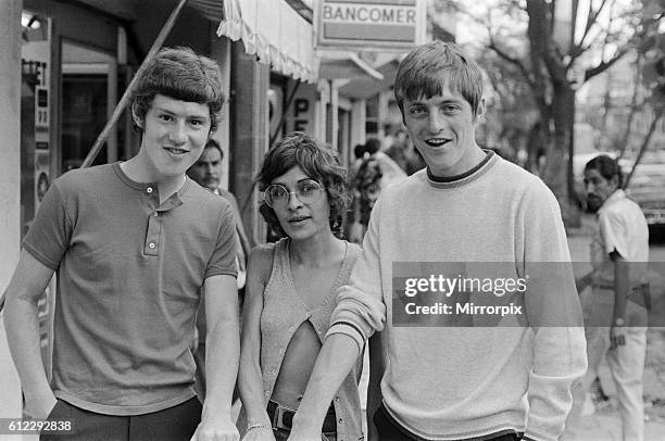 England footballer Brian Kidd and Allan Clarke pose with a woman, showing off their tanned arms, as the team stroll around the Zona Rosa part of...