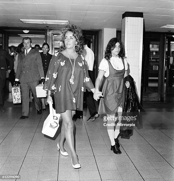 Mini skirted mum and her daughter as the leave the airport. June 1971