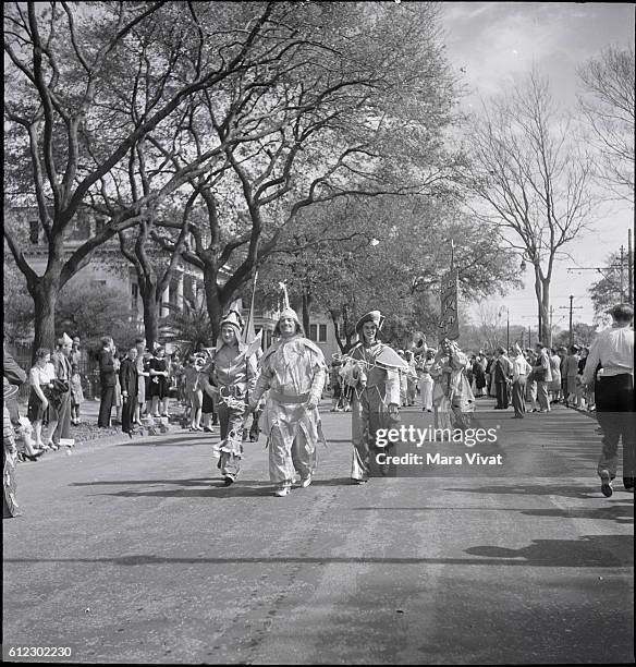 Spectators line a street to watch a Mardi Gras club hold their costume parade in New Orleans, Louisiana, circa 1950.