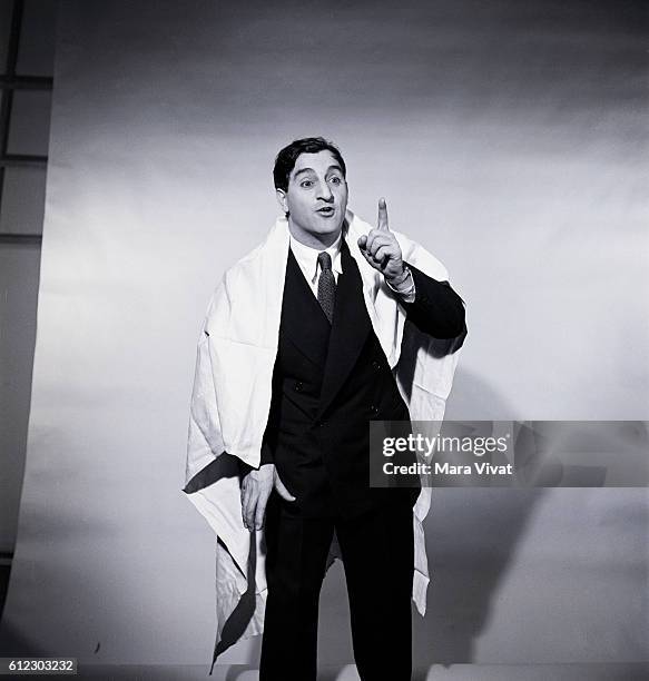 Popular fifities television actor Danny Thomas points his finger upwards and emotes with a bed sheet draped on his shoulders.