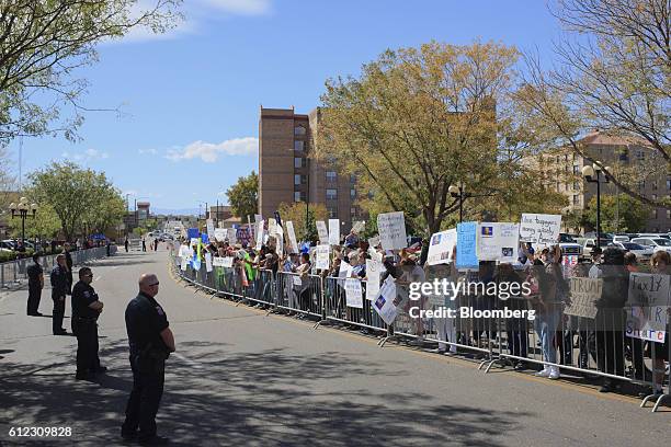 Police officers stand guard as protesters gather outside before the start of a campaign event with Donald Trump, 2016 Republican presidential...