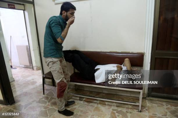 Man reacts as he looks at another man lying on a bench inside the Al Rahma hospital on October 3, 2016 in the city of Qamishli in the Syrian province...