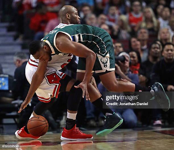 Jabari Parker of the Milwaukee Bucks tries to control a loose ball under pressure from Taj Gibson of the Chicago Bulls during a preseason game at the...