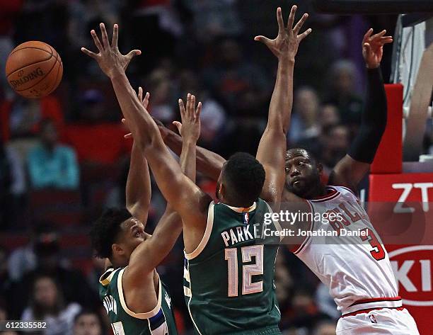 Dwyane Wade of the Chicago Bulls passes the ball under pressure from Malcolm Brogdon and Jabari Parker of the Milwaukee Bucks during a preseason game...