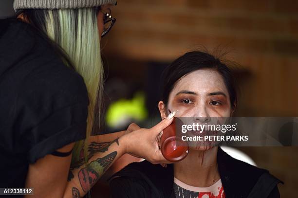 This photo taken on September 17, 2016 shows a "zombie" having makeup applied in "Zedtown", a real-life adventure event based on a video game taking...