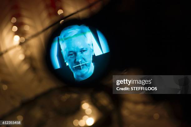 Julian Assange, founder of the online leaking platform WikiLeaks, is seen through the eyepeace of a camera as he is displayed on a screen via a live...